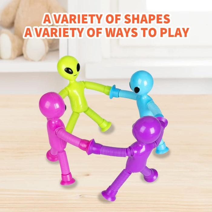 Four colorful alien toys with pop tube limbs and suction cup feet arranged in a circle holding hands on a wood table.