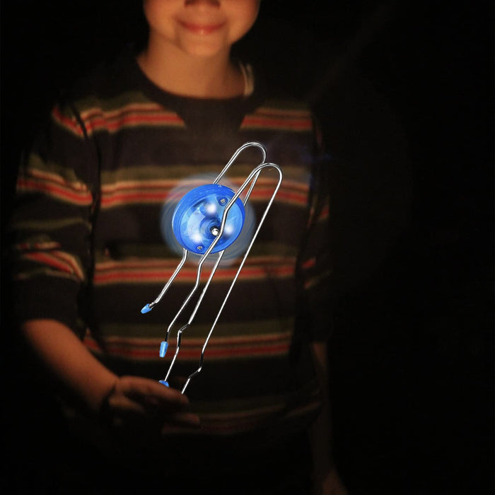 A child holds a glowing blue wheel spinning along silver metal rails against a dark background.