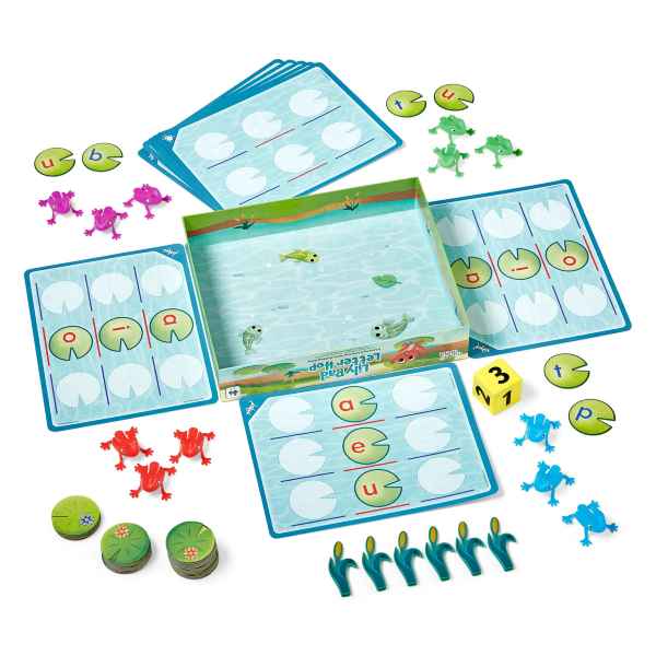 Game set with multicolored toy frogs, lettered lily pad cards, and a yellow die around a pond-illustrated box.