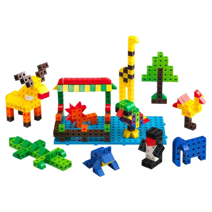 Colorful interlocking cubes assembled into toy animals, a tree, and a shelter on a blue base and white background.