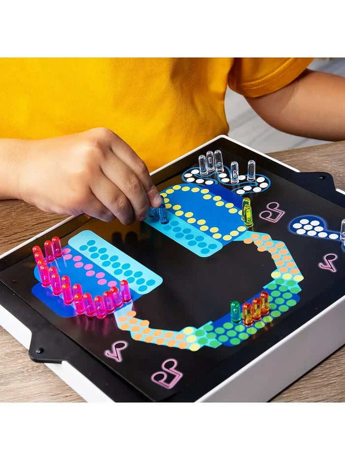 Child inserts colorful translucent pegs into a light-up board to create a glowing headphone and music note design.