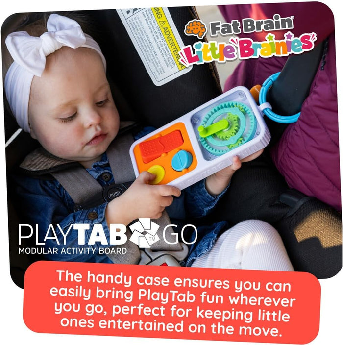 Baby in a car seat holds a white modular activity board featuring an orange slider, blue dial, and green gears.
