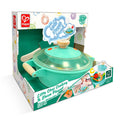 Teal toy cooking pot with wooden handles and clear lid in a white Hape box with steam and sound icons.