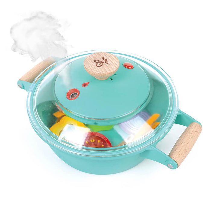 Teal toy cooking pot with wooden handles, transparent lid emitting faux steam, and colorful play food inside.