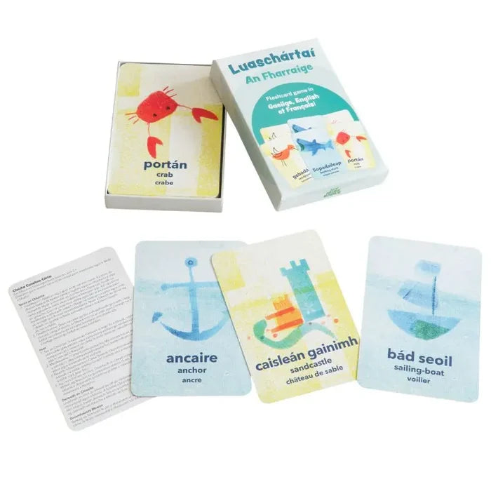 Multilingual flashcards in a white box featuring watercolor sea illustrations: a red crab, blue anchor, and sailboat.