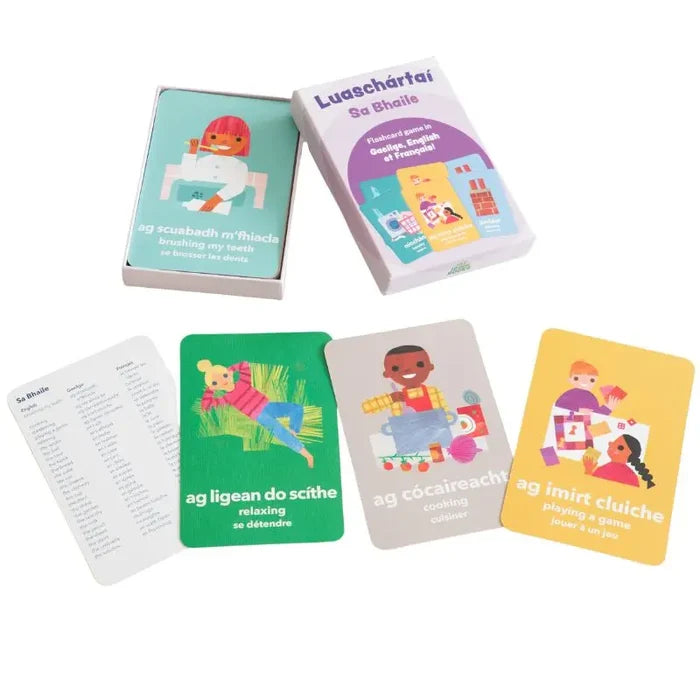 Irish language flashcard box and cards with vibrant illustrations of children cooking, relaxing, and brushing teeth.