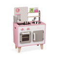 Pink and white wooden toy kitchen with a sink, stove, oven, cupboard, shelves, utensils, and two food boxes.