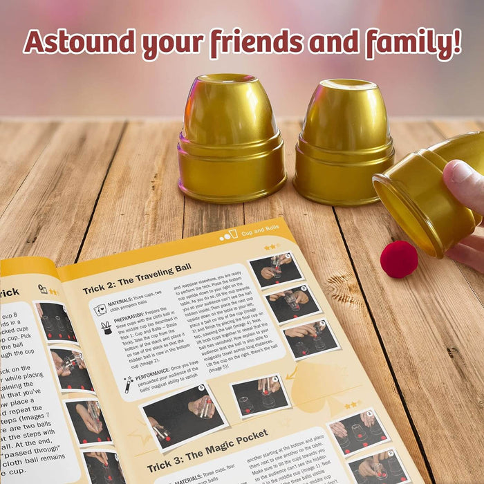 Three metallic gold cups and a red ball shown with an open instruction book on a wooden table.