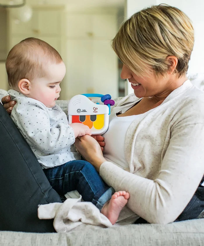 Baby and mother playing with the white Magic Touch Mini Piano featuring colorful keys and a blue handle with beads.