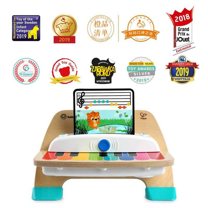 Wooden piano with flat rainbow keys, teal feet, and tiger sheet music, surrounded by toy award logos.