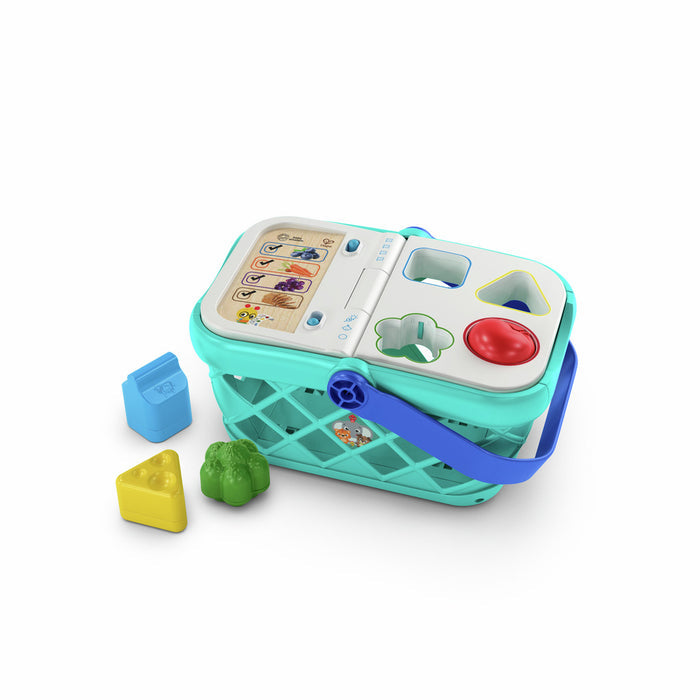 Teal toy shopping basket with shape sorter lid, blue handle, and three colorful plastic food pieces.