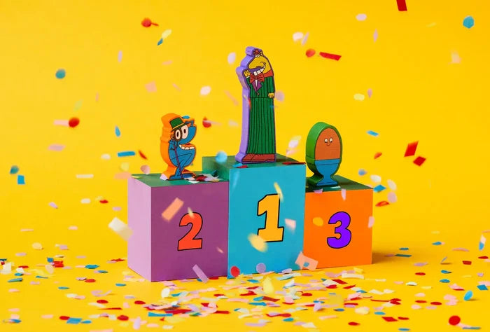 Three whimsical character tokens on a 1-2-3 podium with scattered confetti on a bright yellow background.