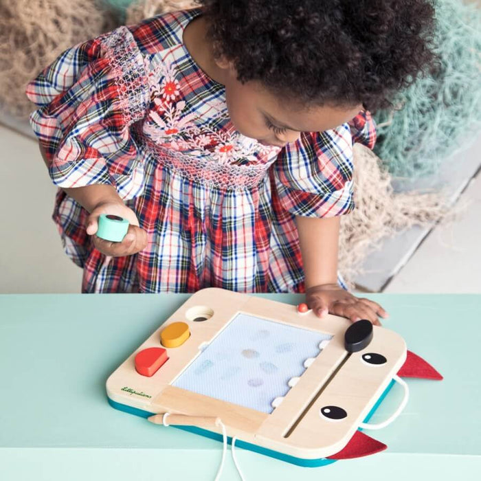 Wolf-shaped wooden magnetic drawing board with red ears, colorful shape stamps, and a stylus being used by a child.