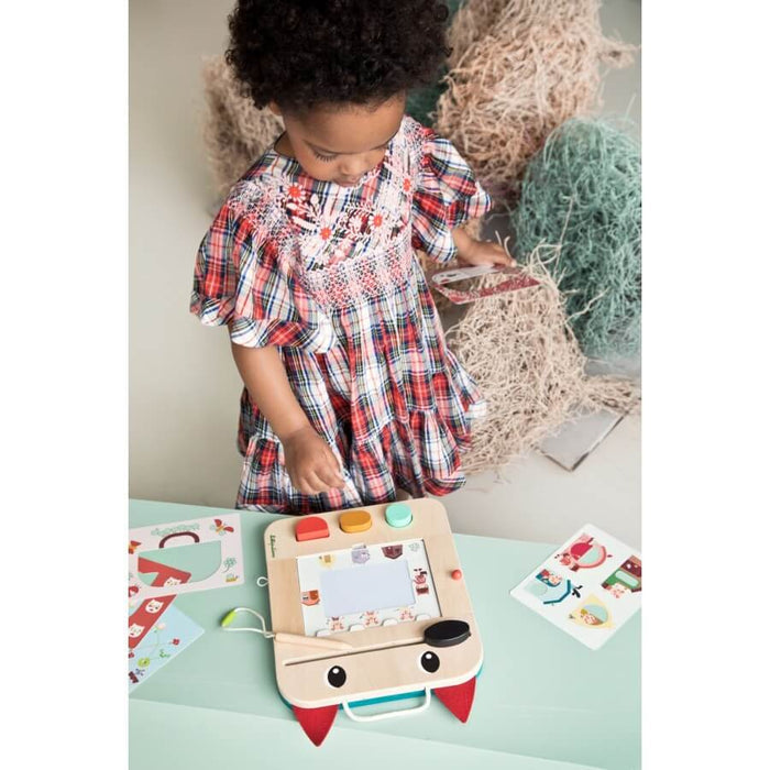 Child playing with a wolf-shaped wooden magnetic drawing board with red felt ears, stylus, and colorful stamps.