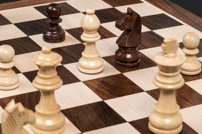 Close-up of light and dark wooden chess pieces on a checkered board, with a white bishop and dark knight in focus.