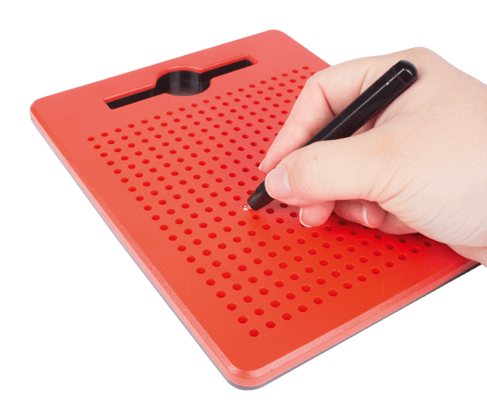 Hand using a black stylus on a red magnetic drawing board with holes to pull up small silver beads.