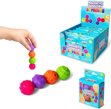 Hand stacking colorful, textured magnetic sensory spheres next to retail display and individual packaging.