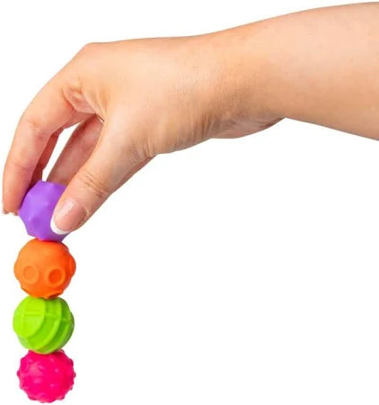 Hand holding a vertical stack of four textured spheres in purple, orange, green, and pink.