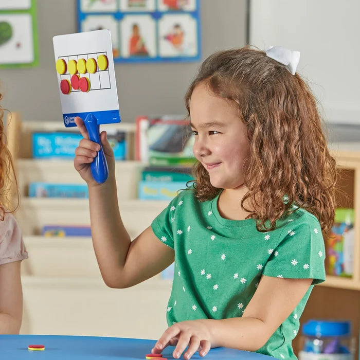 Child holding a blue-handled paddle with a 10-frame grid and magnetic yellow and red circle counters.