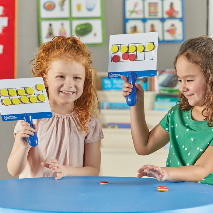 Two girls holding white handheld magnetic ten-frame boards with yellow and red counters.