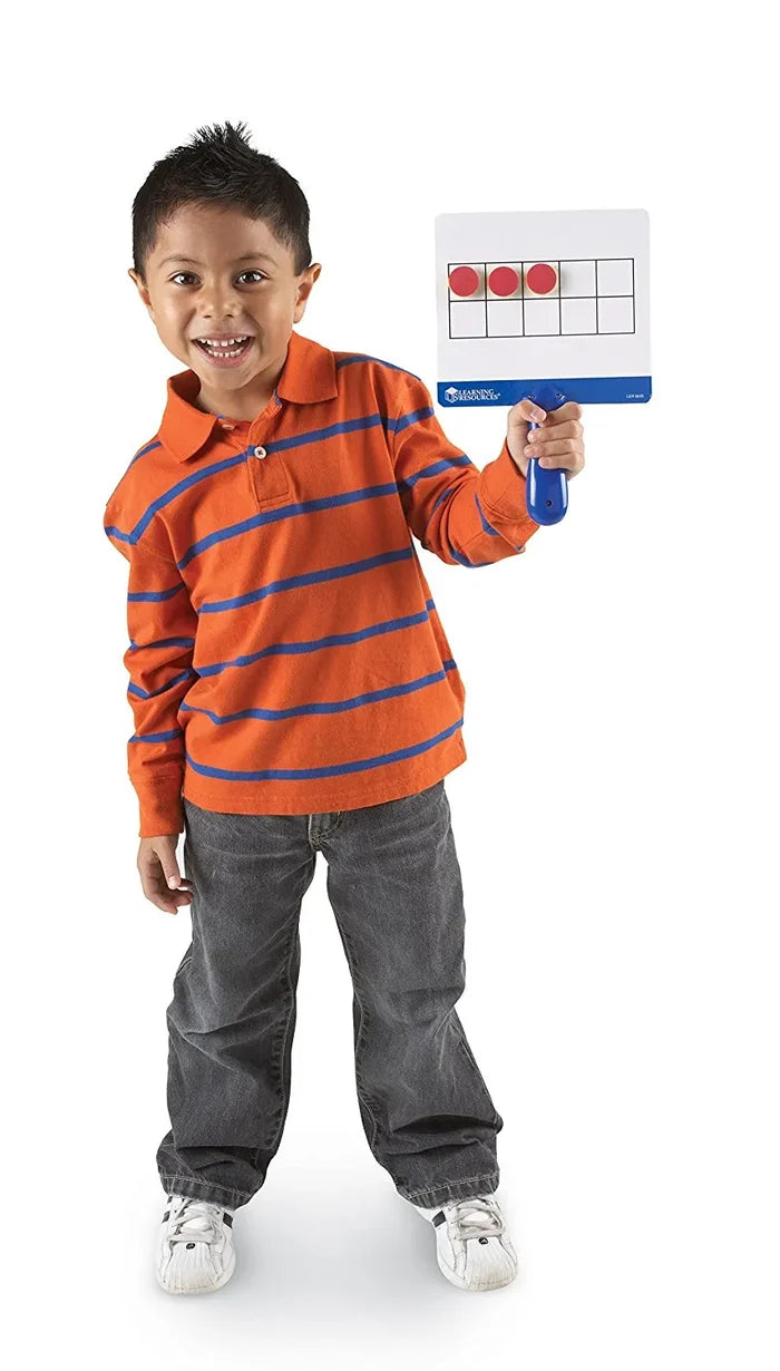 Smiling boy holding a white board with a blue handle, featuring a ten-frame grid with three red magnetic counters.