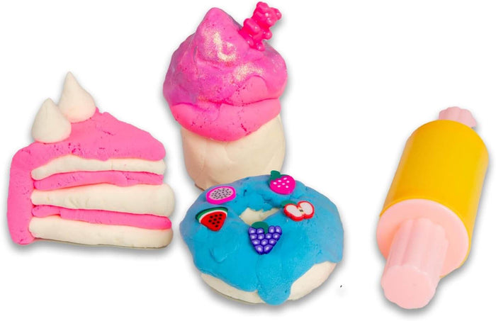 Pink layered cake slice, blue donut with fruit charms, pink cupcake with gummy bear, and a yellow rolling pin tool.