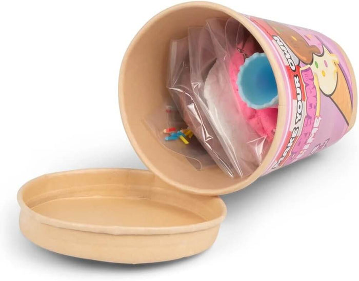 Open tan tub on its side showing bags of pink slime, colorful sprinkles, and a blue cup next to a paper lid.