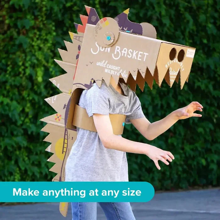 Child wearing a large cardboard dragon head and spiked tail held together by blue plastic fasteners.