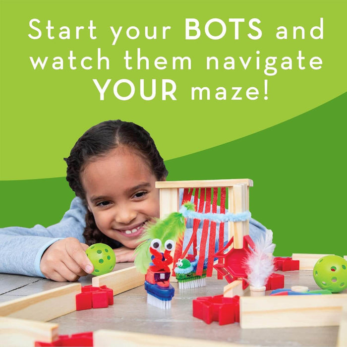 A girl plays with a wooden maze featuring red plastic connectors, green balls, and colorful toothbrush robots.