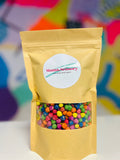 Brown paper pouch with clear window showing rainbow dyed chickpeas. Circular white Mama.Sensory label on the front.