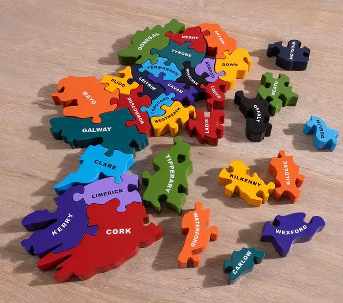 Colorful, chunky wooden Ireland map puzzle with county name pieces, partially assembled on a light wood grain surface.