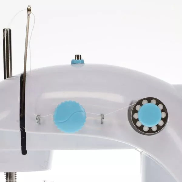 Close-up of a white toy sewing machine with light blue knobs, showing the thread path and metal take-up lever.