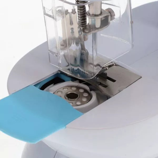 Close-up of a white toy sewing machine with a silver metal bobbin and clear plastic needle safety guard.