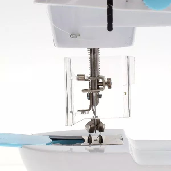 Close-up of a white toy sewing machine needle and presser foot behind a clear plastic safety guard.