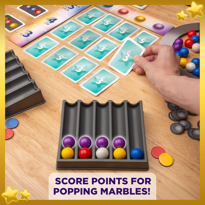 A person plays a board game with colorful marbles, numbered cards, and tokens on a wooden table.