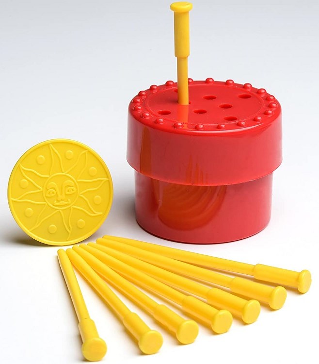 Red plastic container with yellow pegs and a sun-patterned coin toy on a white background.