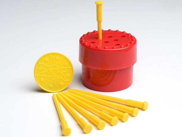 Red magic box with holes, yellow sun-face coin, and seven yellow plastic spikes on a white background.