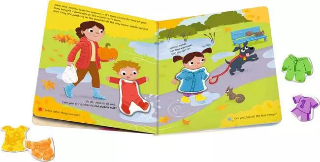 Open children's book with colorful autumn scenes, magnetic play pieces for clothing, and a dog on a path.