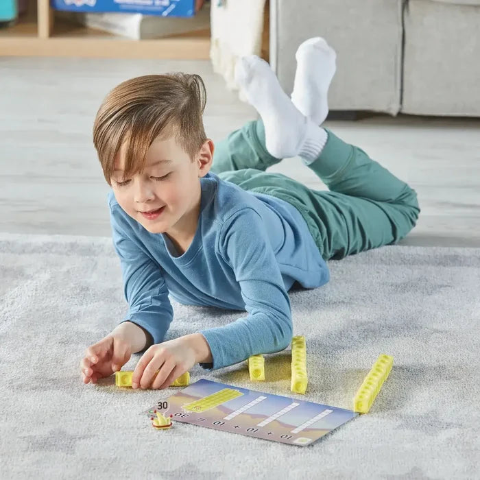 Boy on a rug using yellow connecting cubes and a math activity card to learn number building and addition.