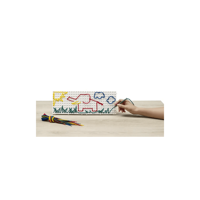 Hand using a stylus to thread green lace on a white board depicting a red elephant, yellow sun, and blue clouds.