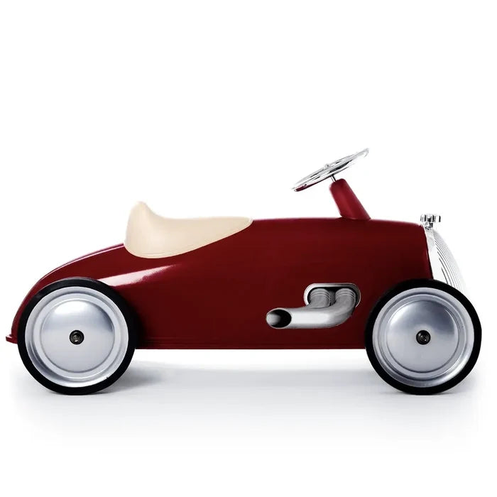 Red vintage-style ride-on car with a cream seat, chrome grille, side exhaust pipes, and large silver wheels.