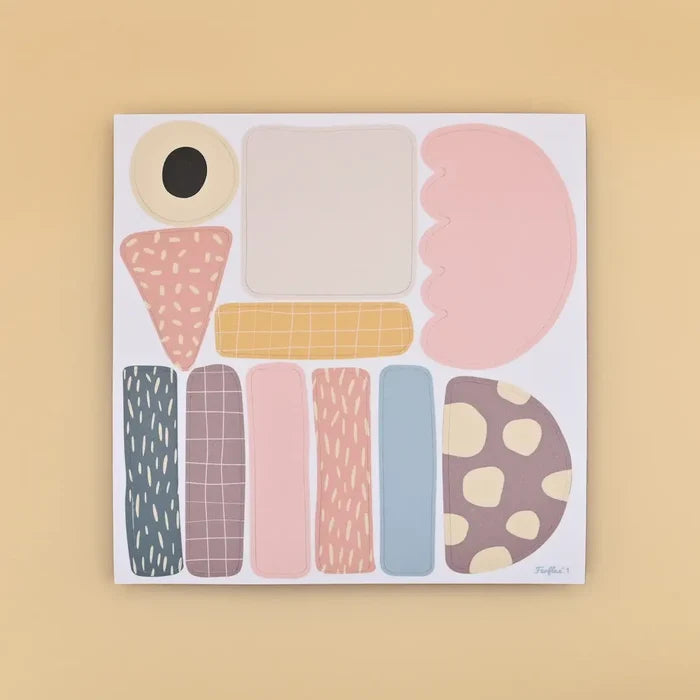 White magnetic board decorated with colorful abstract magnets in pastel colors and patterns like dots and grids.