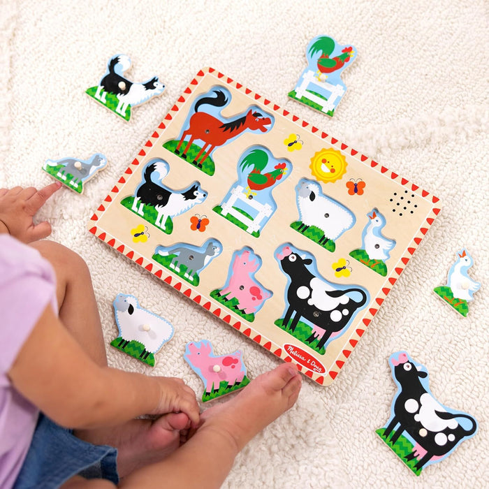 Wooden farm animal sound puzzle board with colorful pieces on a white rug with a child playing.