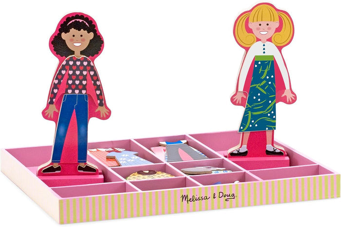 Two wooden magnetic dolls stand in a pink tray with compartments filled with colorful clothing pieces and accessories.