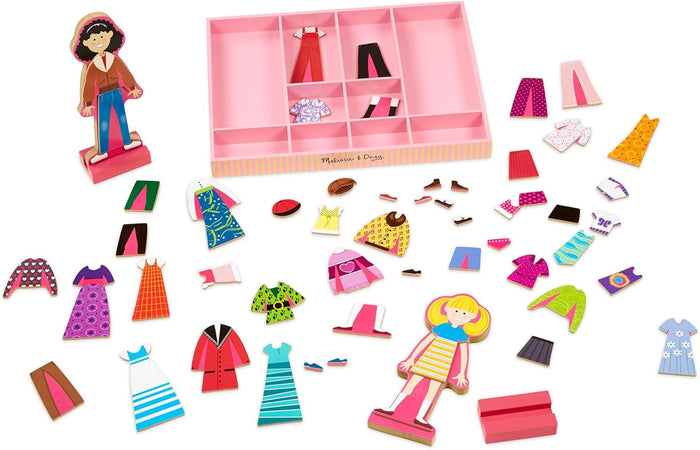 Two wooden magnetic dolls, a pink storage tray, and many colorful outfits and accessories scattered around.