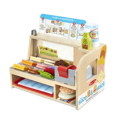 Light wood toy deli counter with colorful felt food slices, a pretend meat slicer, and play condiments.