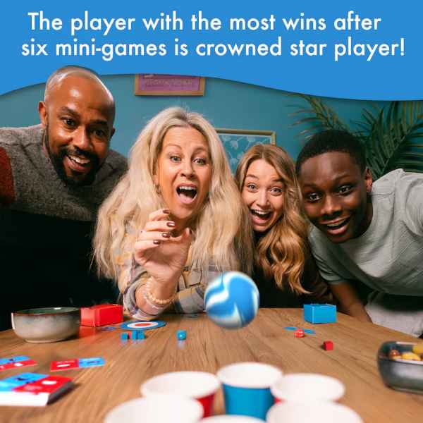 Four people smiling while playing a game with a blue swirly ball, cups, and colorful pieces on a wooden table.