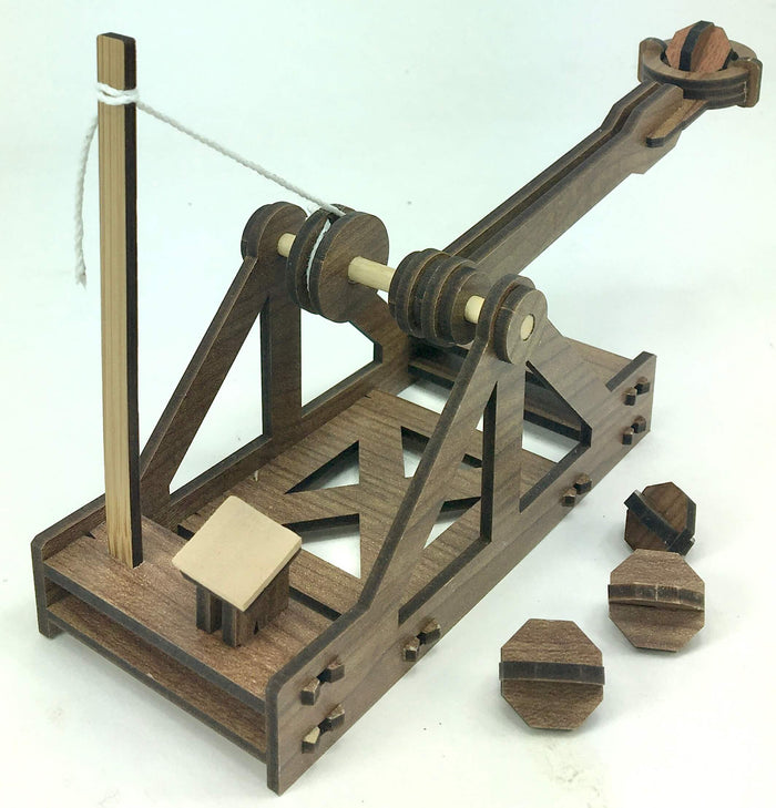 Dark wood model catapult with a throwing arm, white string, and small octagonal projectiles on a white background.