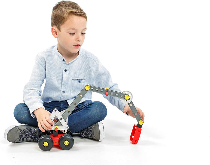 A young boy playing with a toy crane made of grey beams, red base, and yellow bolts on a white background.