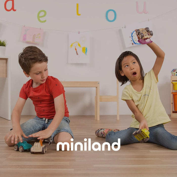 Two children play with toy cars on a wooden floor in a playroom with the Miniland logo.